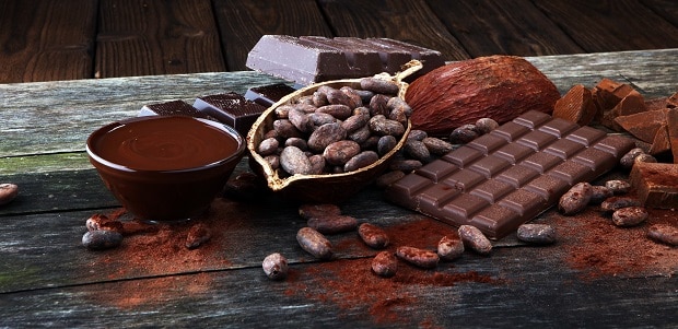 бобы горького шоколада, рядом шоколадная плитка и растопленный шоколад